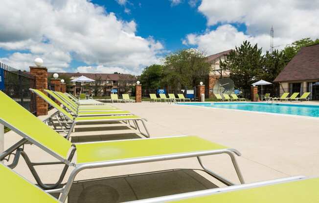 a row of yellow lounge chairs next to a swimming pool