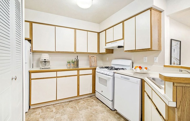 A kitchen with white appliances and wooden cabinets at South Bridge Apartments in Fort Wayne, IN