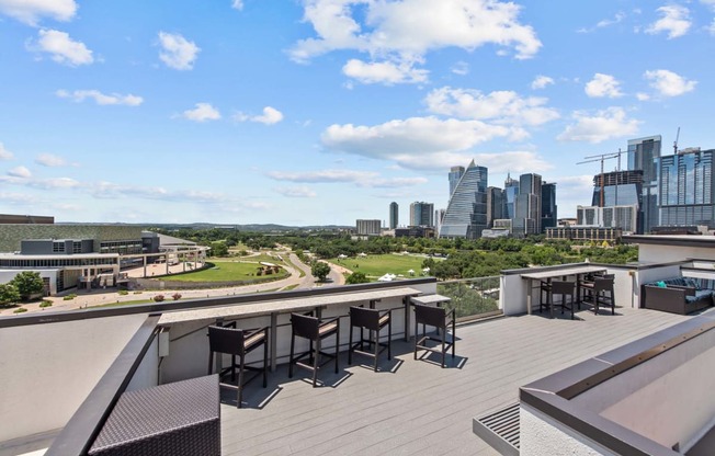 a rooftop terrace with tables and chairs and a view of the city