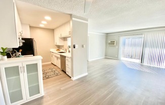 an empty living room and kitchen with a sliding glass door at The Flats on Addison, Sherman Oaks, CA