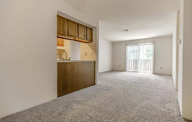 A room with a grey carpet and wooden cabinets