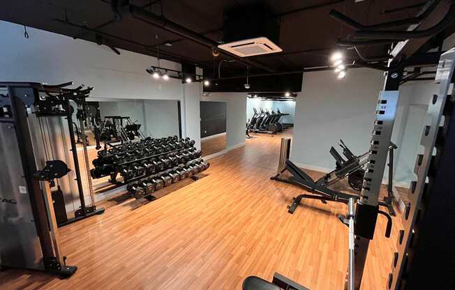 A gym with a variety of equipment including treadmills, weights, and exercise machines.