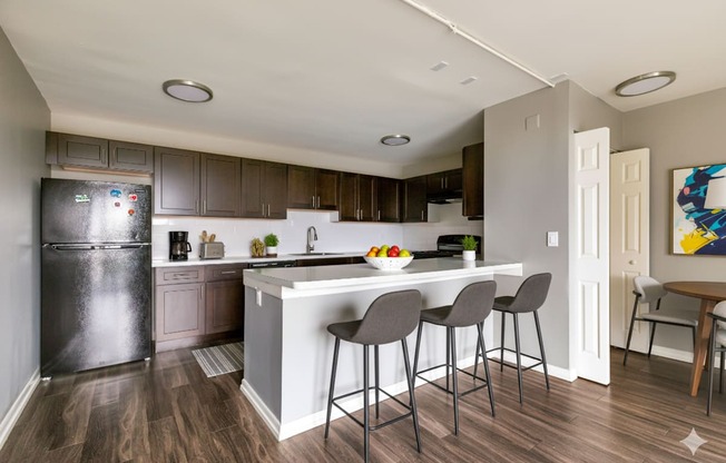 A kitchen with a white island and grey bar stools.
