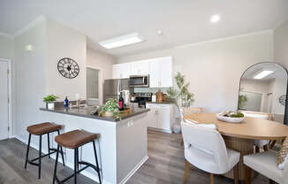A kitchen with a bar area and a dining table with chairs.