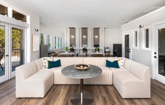 a living room with a large white couch and a round table with a bowl of fruit on