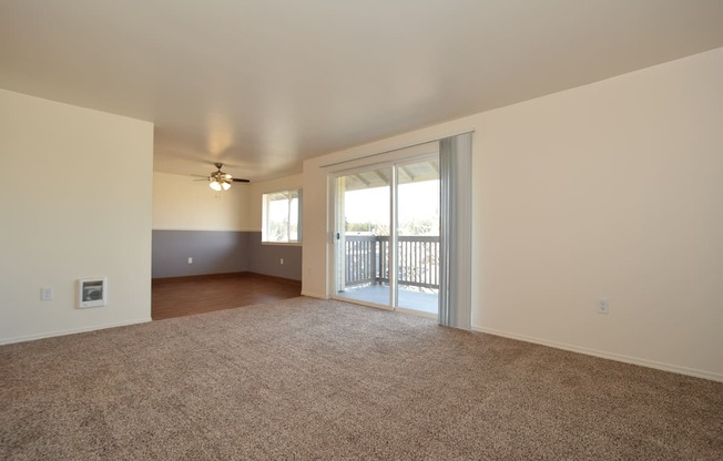 an empty living room with a sliding glass door and a balcony