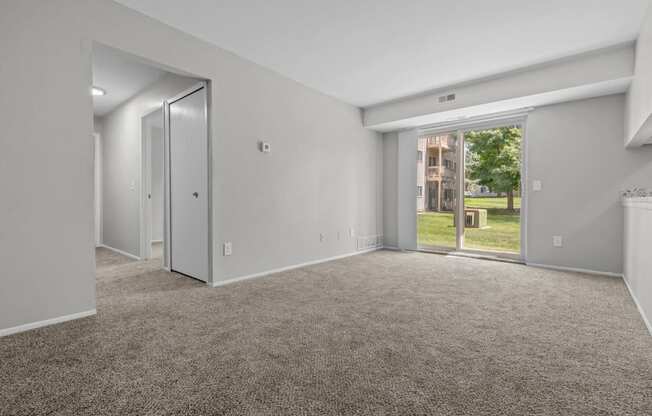 the living room of an apartment with carpet and a door to the yard