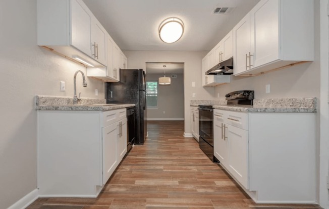 A kitchen with white cabinets and a marble countertop.