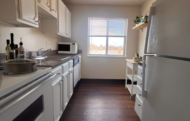 a kitchen with white cabinets and a window