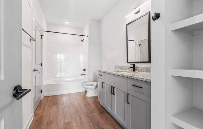 A white bathroom with a wooden floor and a walk-in shower.