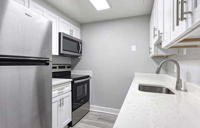 A kitchen with a stainless steel refrigerator, microwave, oven, and sink.