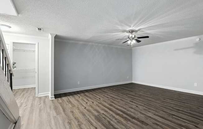 A room with a ceiling fan and wooden flooring.
