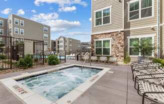 A swimming pool surrounded by lounge chairs and apartment buildings.
