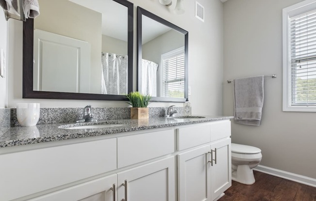 a bathroom with two mirrors and a sink and a toilet