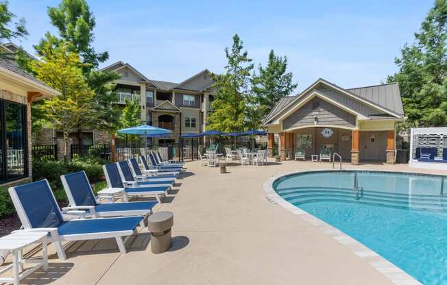 a swimming pool with chaise lounge chairs and umbrellas in front of a building