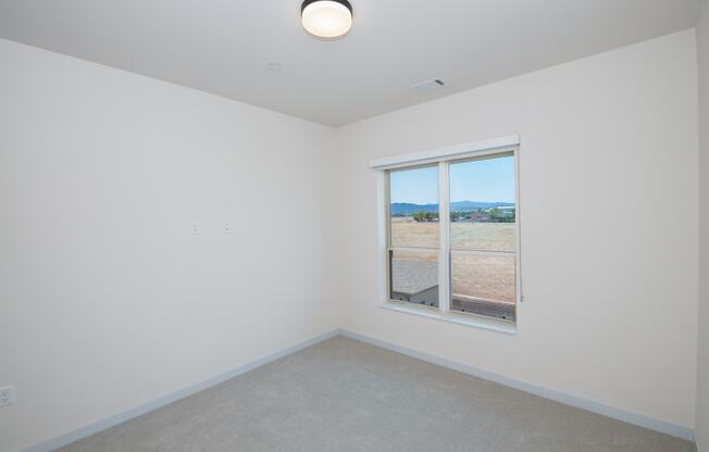 an empty room with a window overlooking a field at The Crossings at Windsong, Prescott Valley