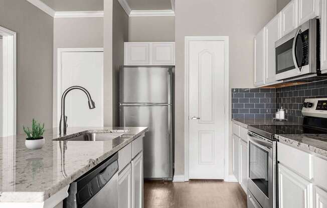 A kitchen with a refrigerator, sink, and oven.