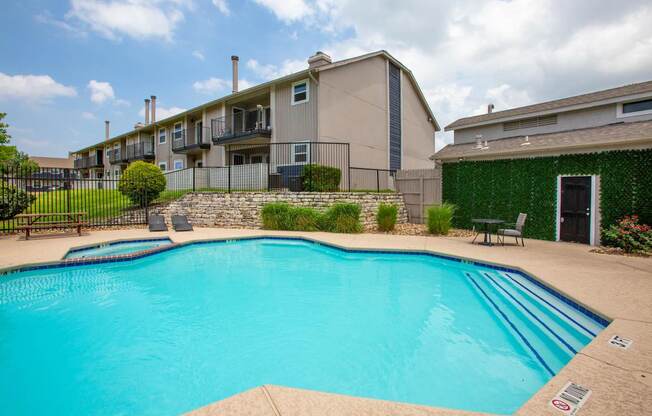 A swimming pool in a residential area with a green wall on the right.