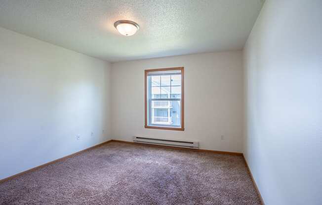 A room with a window and a carpet on the floor. Fargo, ND Stonebridge Apartments