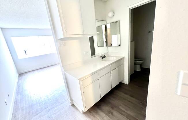 Bachelor style unit vanity white counter tops and cabinets with sink and faucet outside bathroom