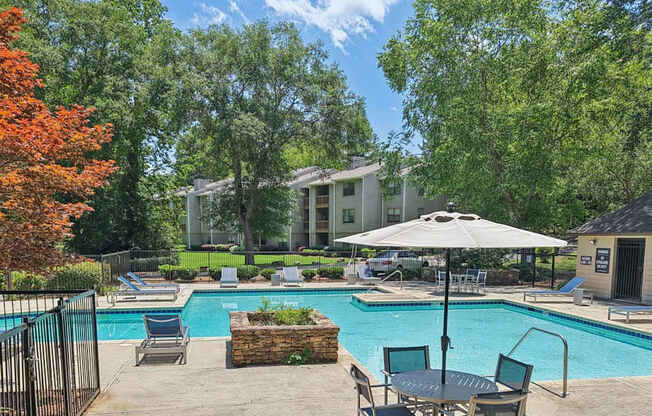 A pool surrounded by trees and chairs.