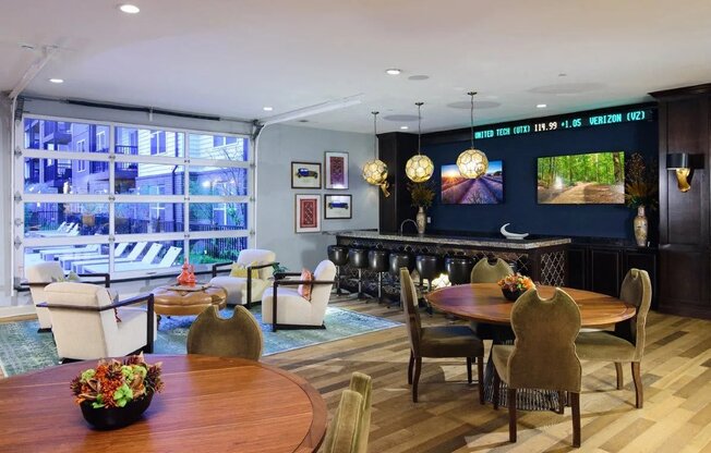 A living room with a wooden table and chairs, a sofa, and a television displaying a forest scene.