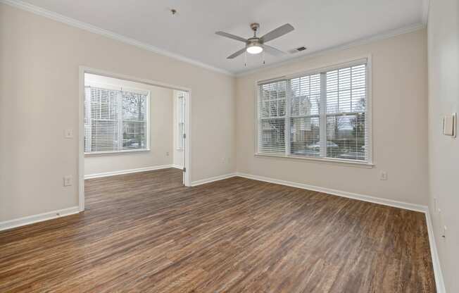 an empty living room with a ceiling fan and a window