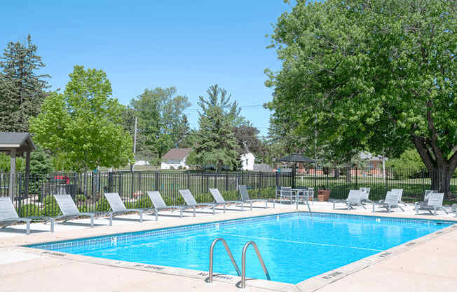a swimming pool with chaise lounge chairs and trees in the background