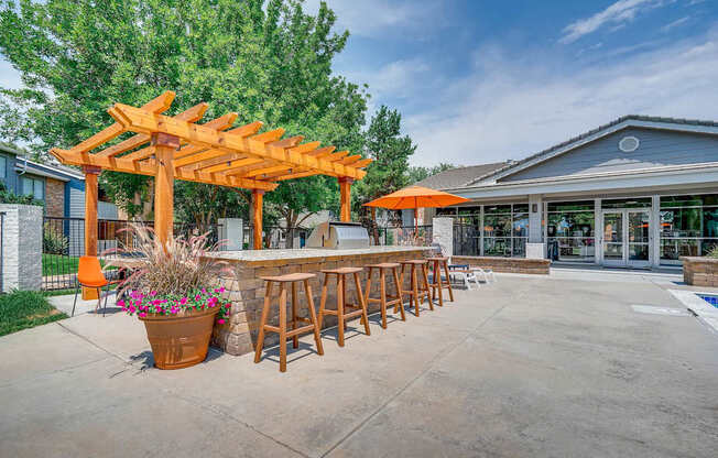 A patio with a bar and seating area under a wooden pergola.
