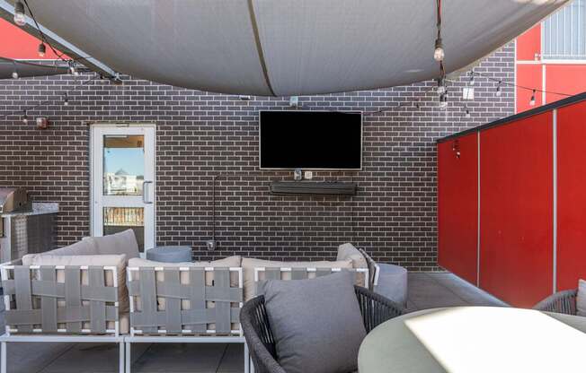 a patio with chairs and a television on a brick wall