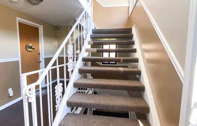 A staircase with a carpeted runner and white railings.