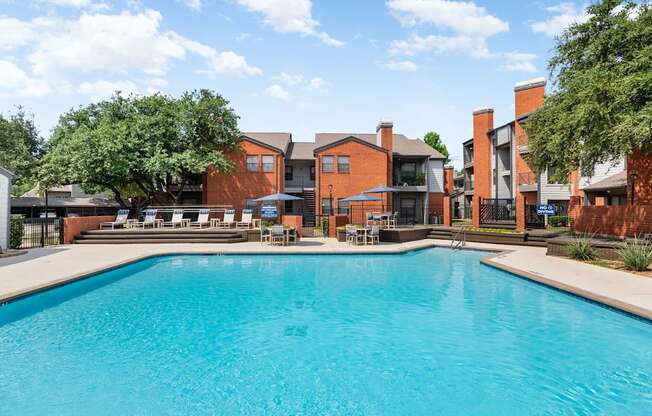 Community pool with sundeck loungers, shaded tables, and landscaped courtyard setting.