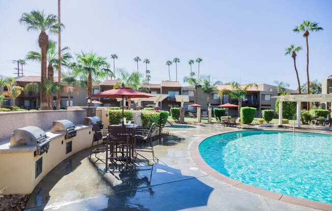 a resort style pool with tables and umbrellas at the resort