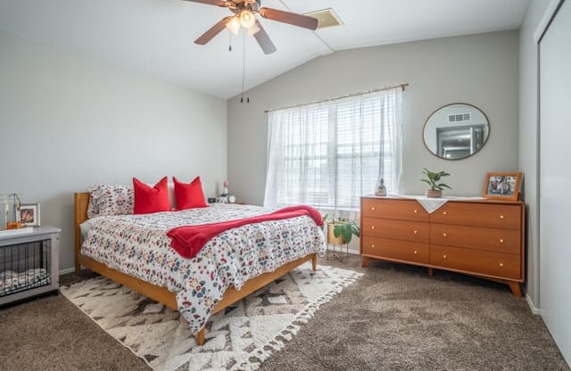 A bedroom with a bed, dresser, and ceiling fan.