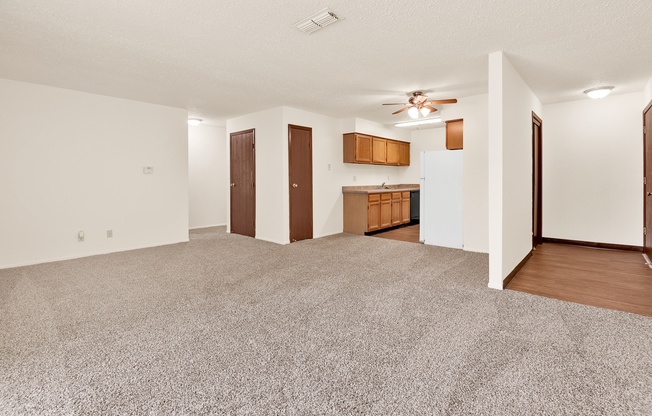 A spacious room with a carpeted floor and a ceiling fan.