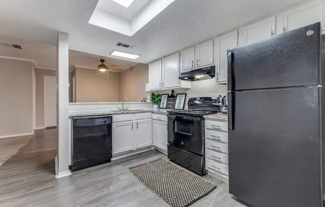 a kitchen with white cabinets and black appliances