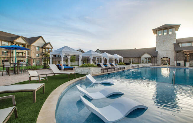 a resort style pool with lounge chairs and umbrellas