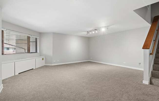A spacious room with a staircase on the right side.