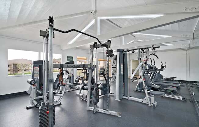 A gym with a variety of equipment including a weight machine, a treadmill, and a stationary bike.