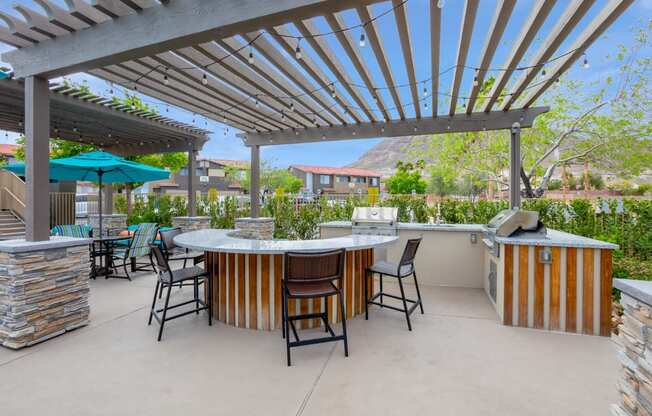 a patio with a bar and chairs and a pergola