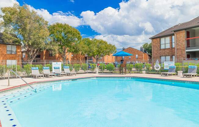A large swimming pool surrounded by lounge chairs and trees.