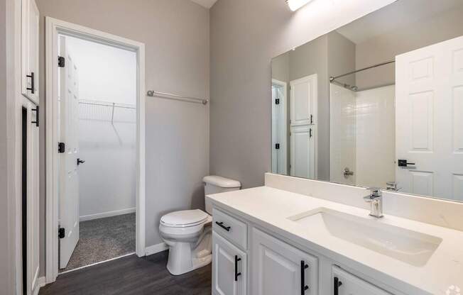 A white bathroom with a toilet, sink, and mirror.