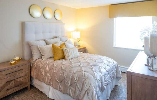 A bedroom with a large bed, a nightstand, and a window.