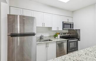 A kitchen with a stainless steel refrigerator, microwave, oven, and sink.