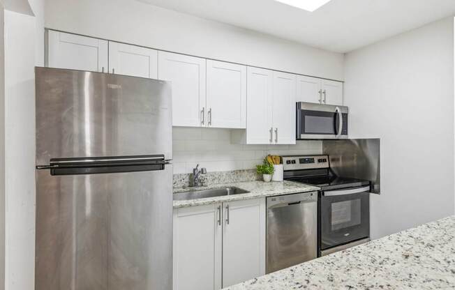 A kitchen with a stainless steel refrigerator, microwave, oven, and sink.
