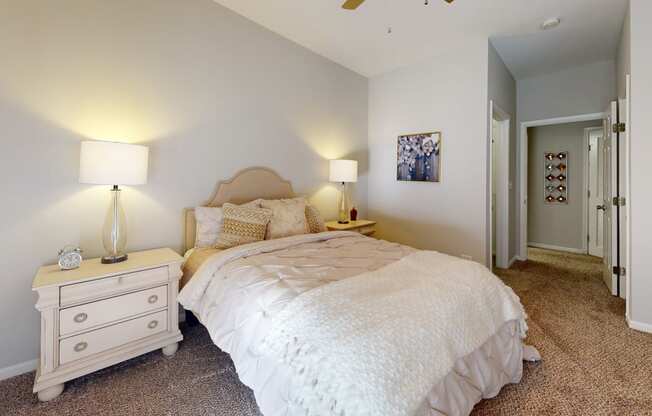 a bedroom with a bed and a dresser with two lamps