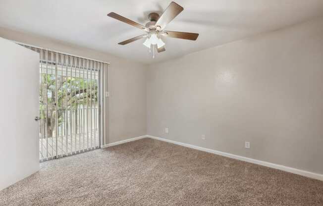 an empty living room with a ceiling fan and a window