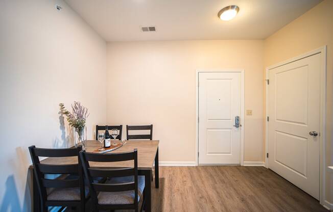 Dining room with table against wall, wine glasses on table, door on the right side of room.