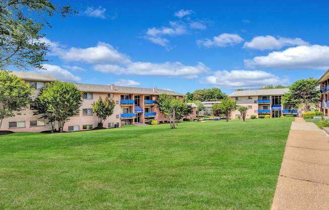 a grassy area with trees and buildings in the background