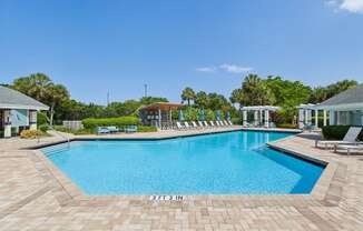 a large swimming pool with chairs around it in front of a house